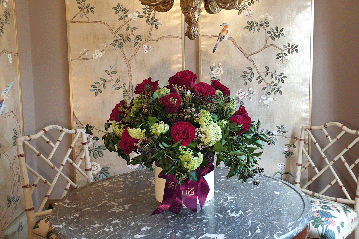 Flowers in elegant hatbox placed on table