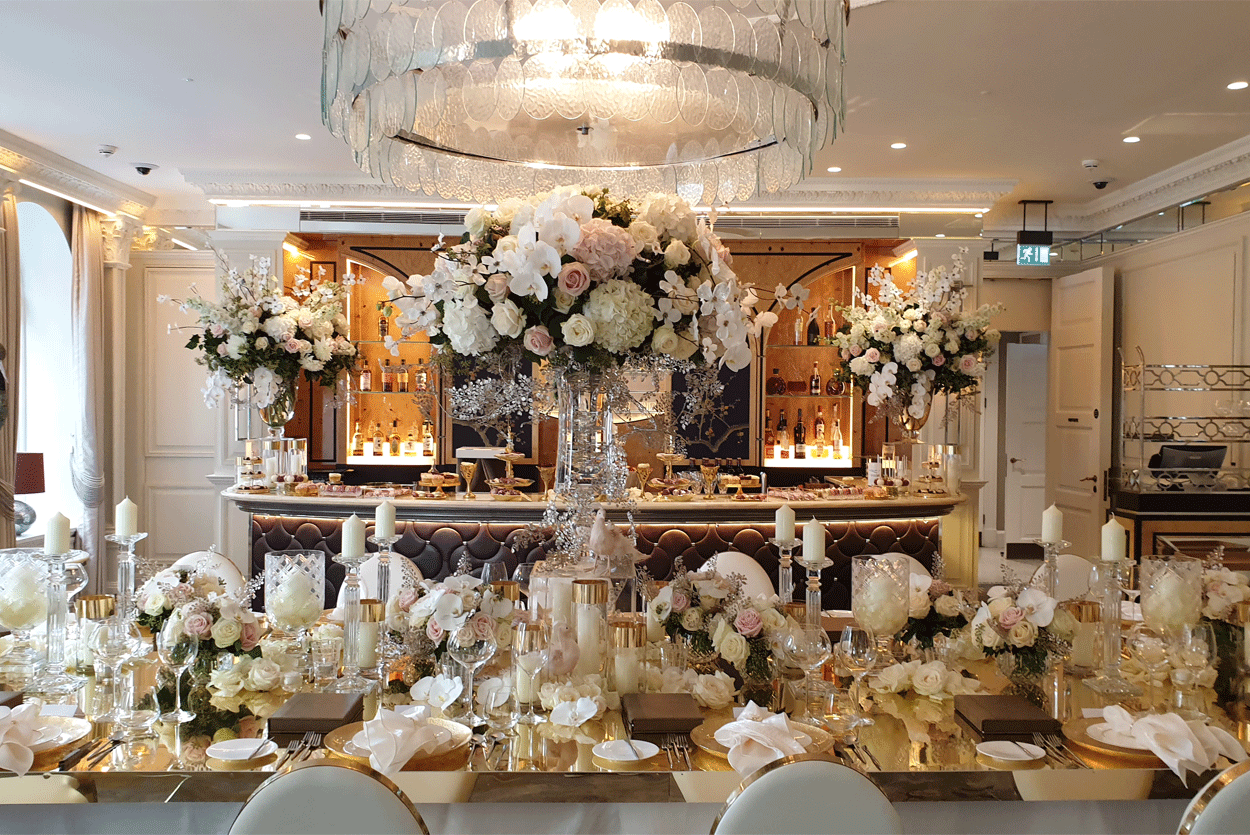 Luxury tall wedding flowers and candles set on gold oval table top in Belmond hotel